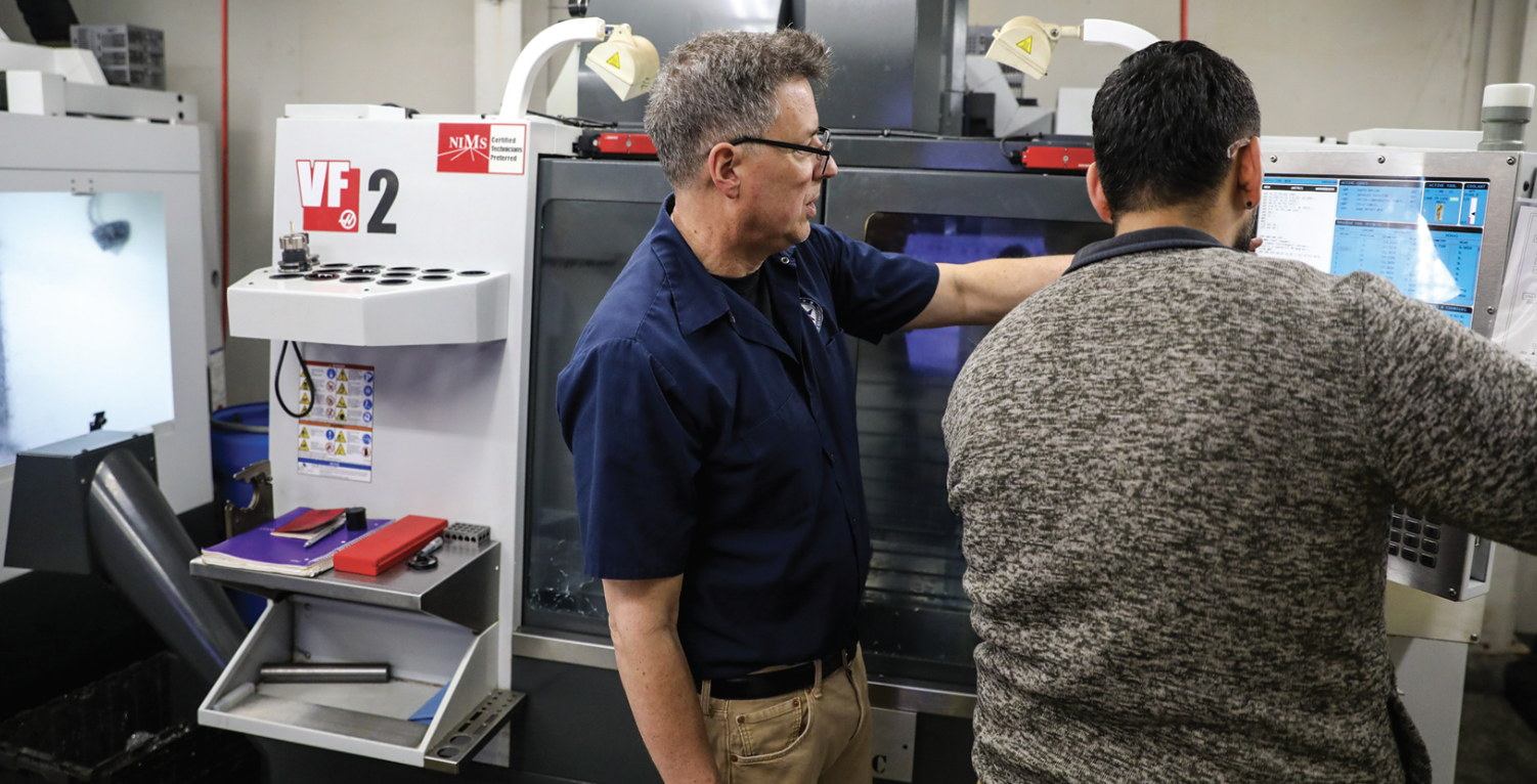 Dean of Machining Pat Dorris (left) giving one-on-one instruction with 10th week student Eric S. on one of WFW’s Haas VF2.